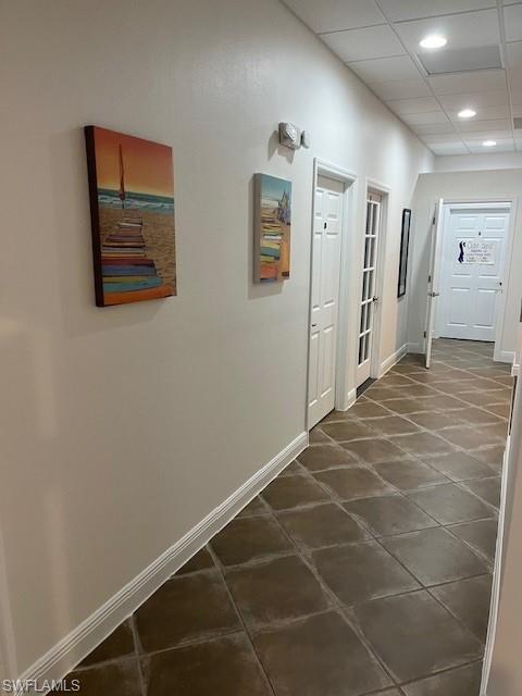 Hall featuring baseboards and a paneled ceiling