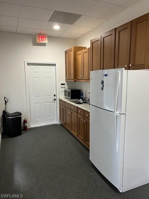Kitchen with a drop ceiling and white fridge