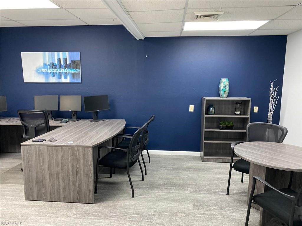 Office space with a drop ceiling, carpet, and baseboards