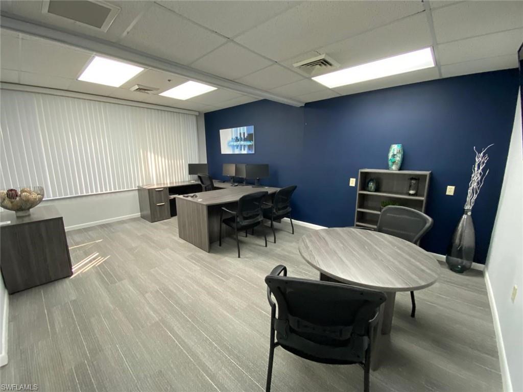 Office featuring a drop ceiling, baseboards, and light wood finished floors