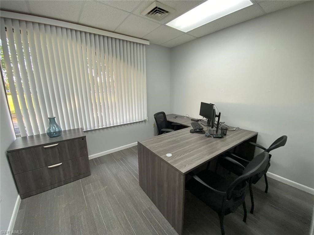 Office area featuring a drop ceiling, baseboards, wood finished floors, and plenty of natural light