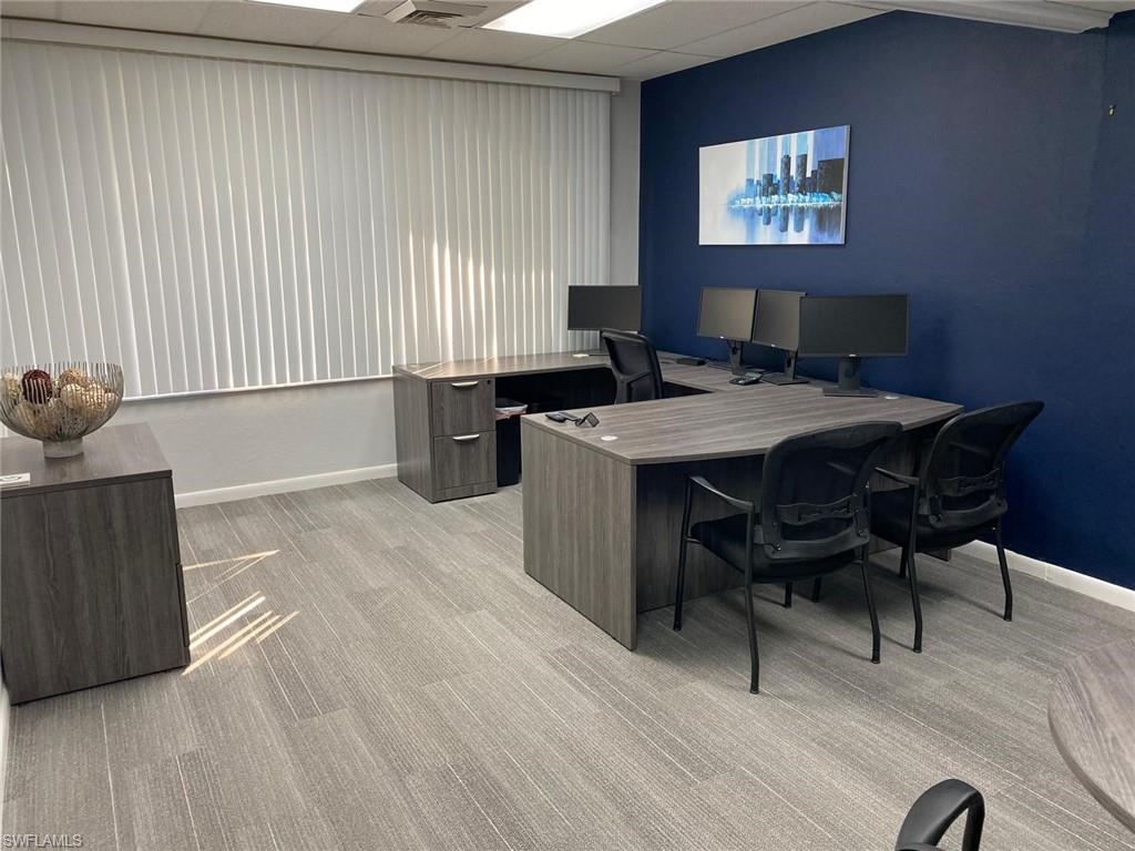 Carpeted office space featuring a drop ceiling and baseboards