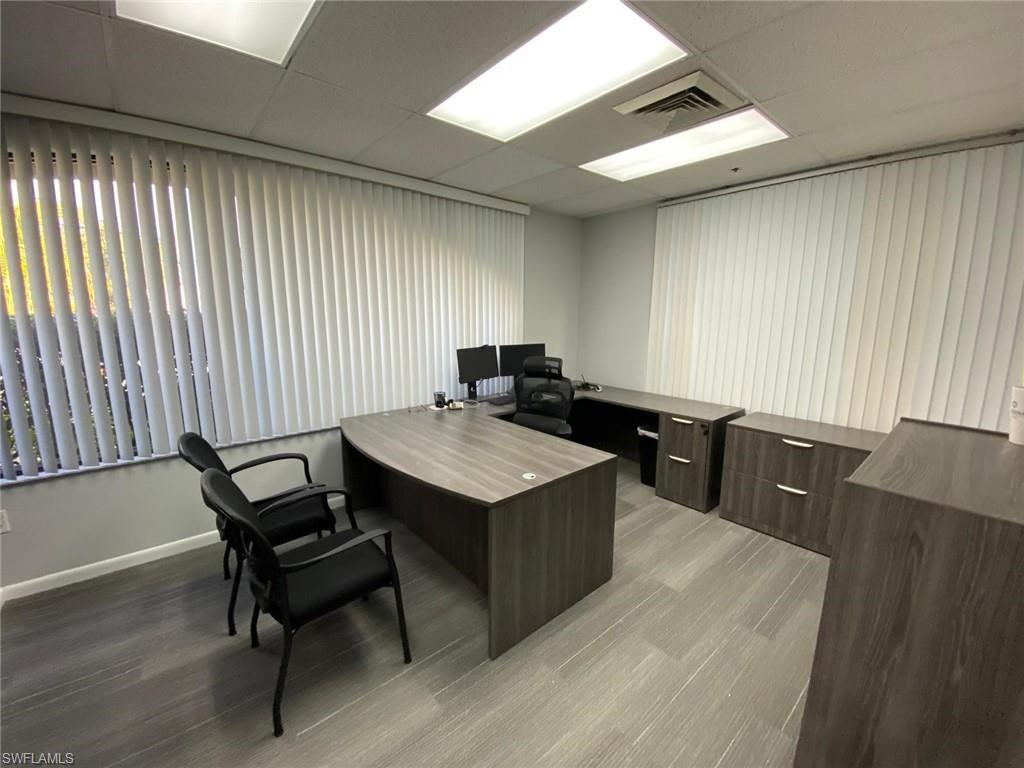 Office area with light wood-style floors, a drop ceiling, and baseboards