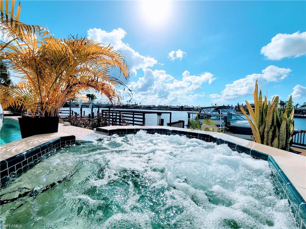View of pool featuring a hot tub and a water view