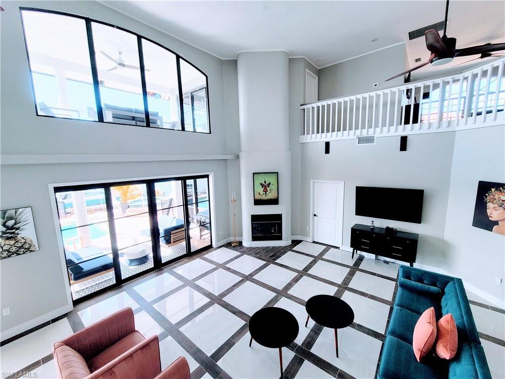 Tiled living room with a high ceiling, ceiling fan, and a large fireplace