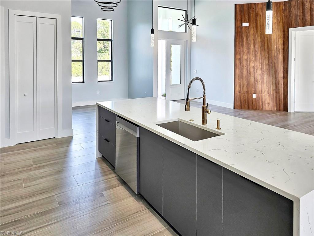 Kitchen featuring dishwasher, pendant lighting, light wood-style flooring, modern cabinets, and a sink