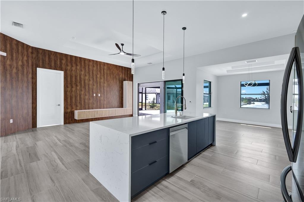 Kitchen featuring stainless steel dishwasher, a sink, visible vents, freestanding refrigerator, and modern cabinets