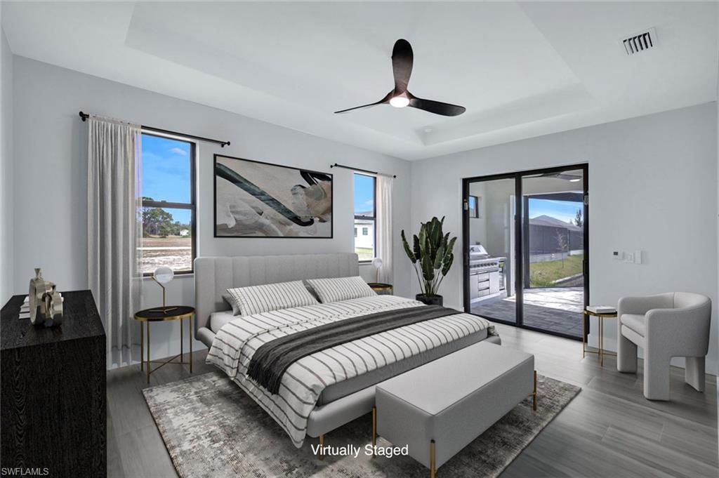 Bedroom with a tray ceiling, visible vents, wood finished floors, and access to exterior