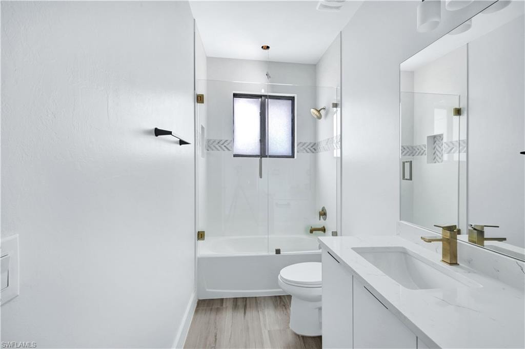 Full bathroom with toilet, vanity, bathing tub / shower combination, and wood finished floors