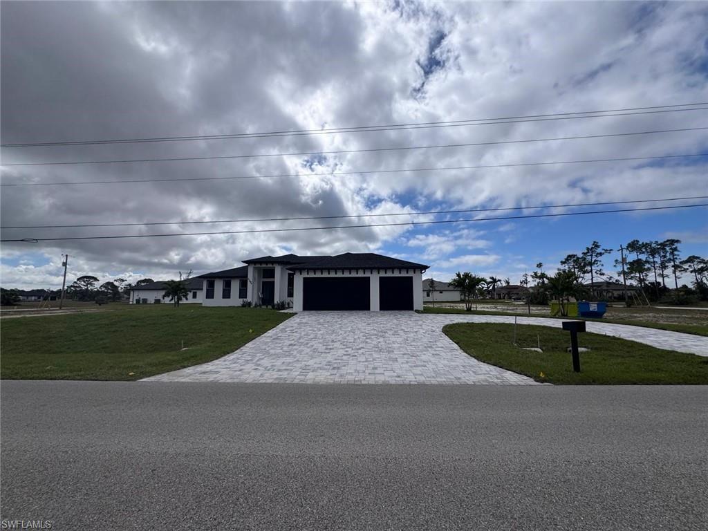 View of front facade featuring a front lawn, decorative driveway, and an attached garage