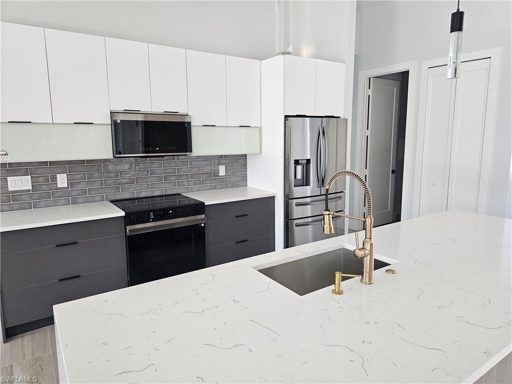 Kitchen with electric range, a sink, gray cabinets, backsplash, and stainless steel fridge with ice dispenser