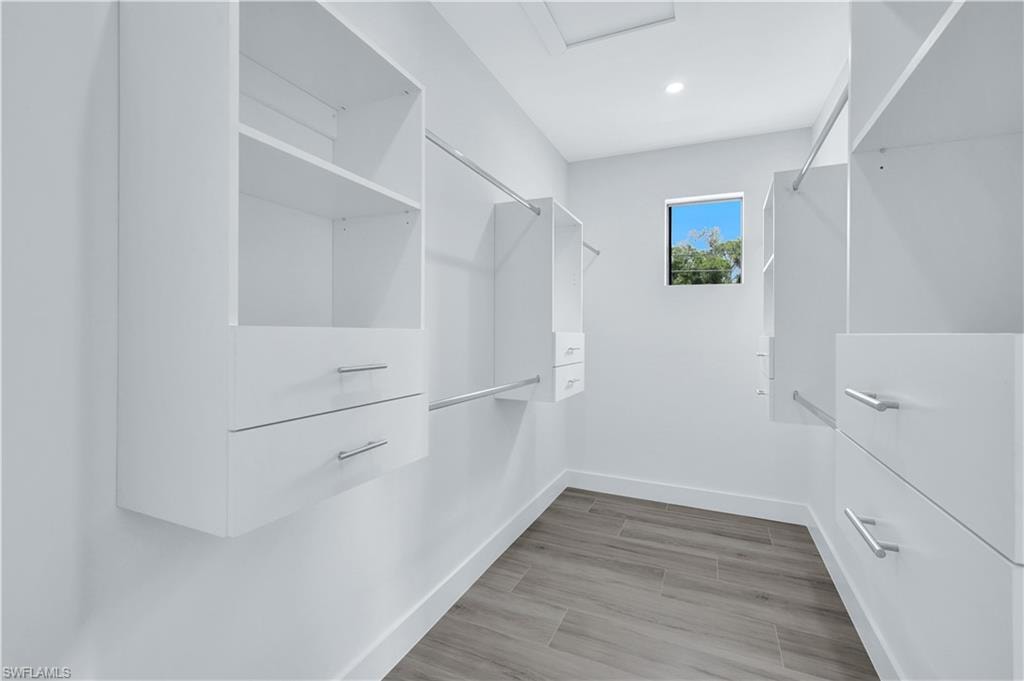 Walk in closet featuring attic access and light wood-type flooring
