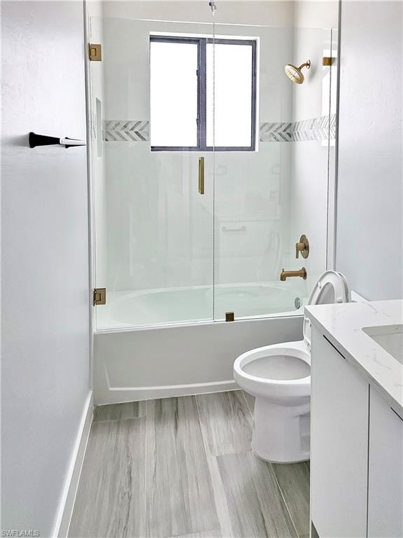 Bathroom with enclosed tub / shower combo, toilet, and vanity