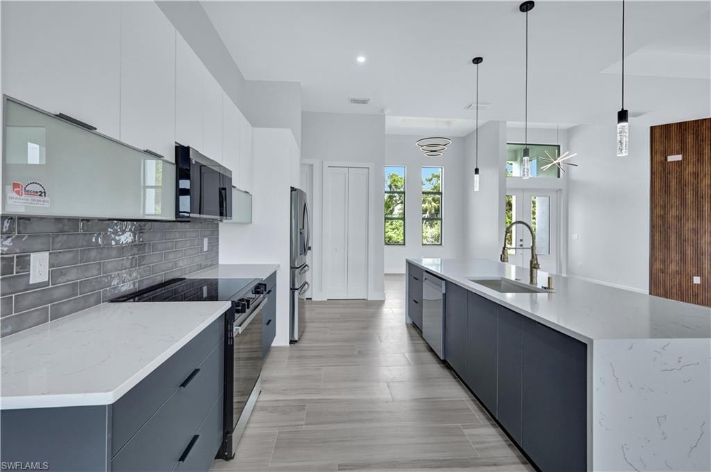 Kitchen featuring a sink, stainless steel appliances, tasteful backsplash, and modern cabinets