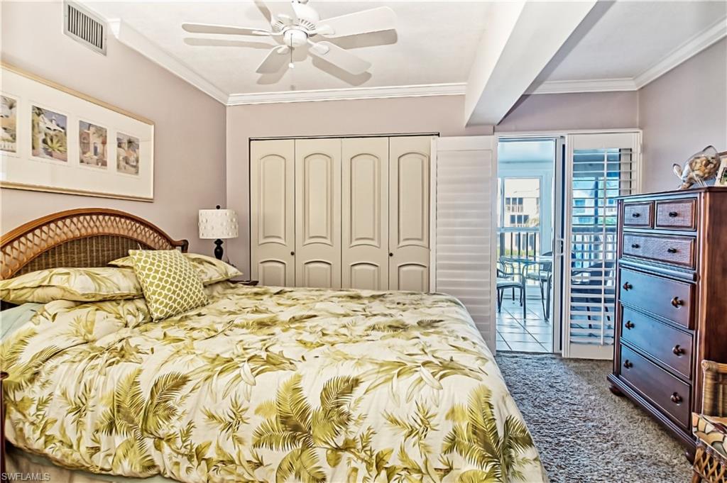 Carpeted bedroom with a ceiling fan and ornamental molding