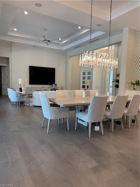 Dining room with recessed lighting, a raised ceiling, and wood finished floors