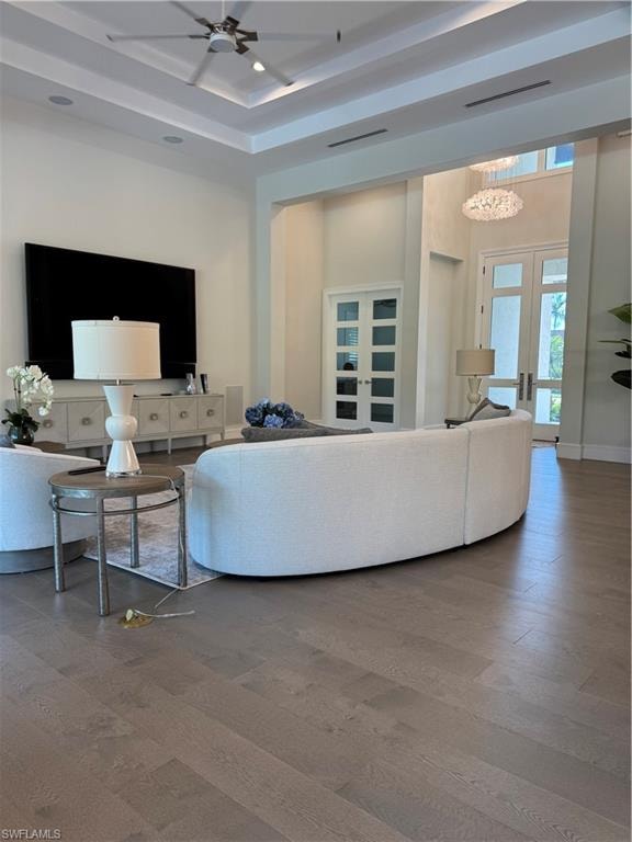 Living area with a ceiling fan, wood finished floors, visible vents, baseboards, and french doors