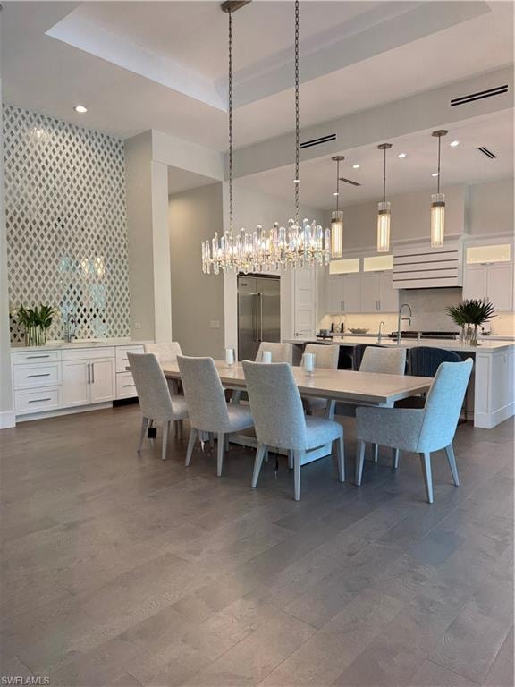 Dining room featuring dark wood finished floors, a tray ceiling, wallpapered walls, recessed lighting, and an accent wall