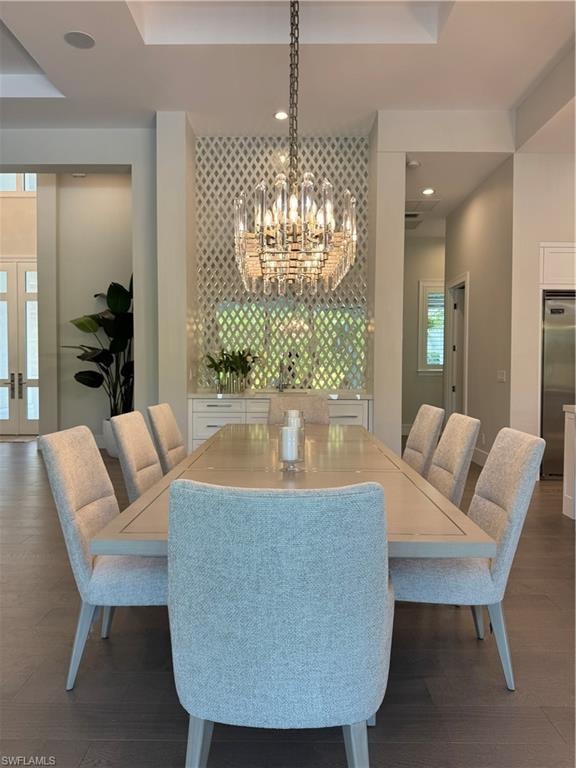 Dining space featuring an inviting chandelier, recessed lighting, dark wood-style floors, and a raised ceiling
