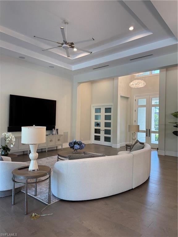 Living room with french doors, baseboards, a raised ceiling, and a ceiling fan