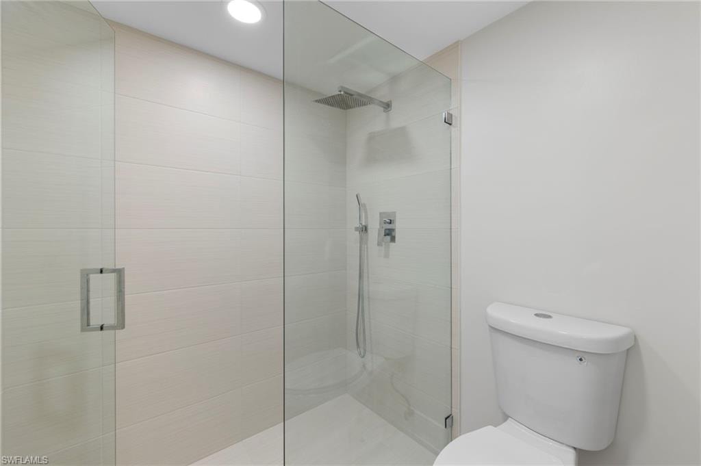 Bathroom featuring a shower with door and toilet