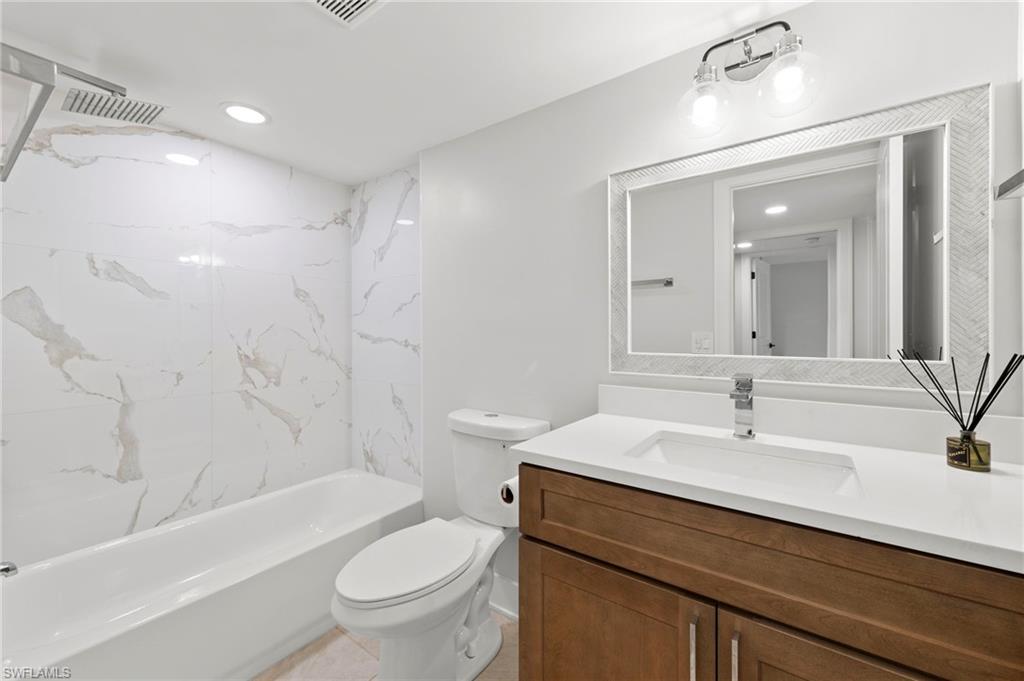 Full bathroom with vanity, toilet, tile patterned floors, and tiled shower / bath