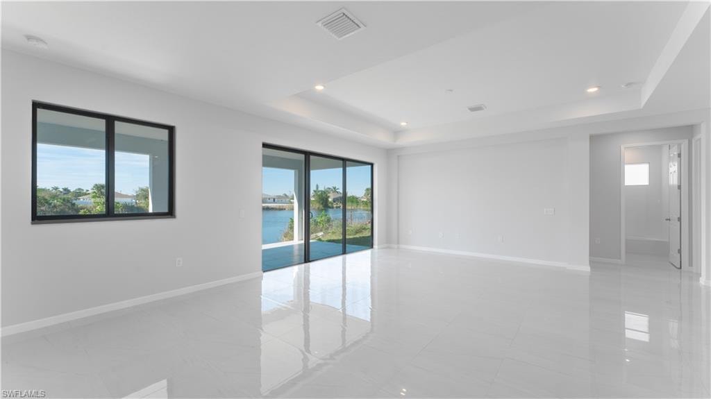 Empty room with a water view, a raised ceiling, and plenty of natural light
