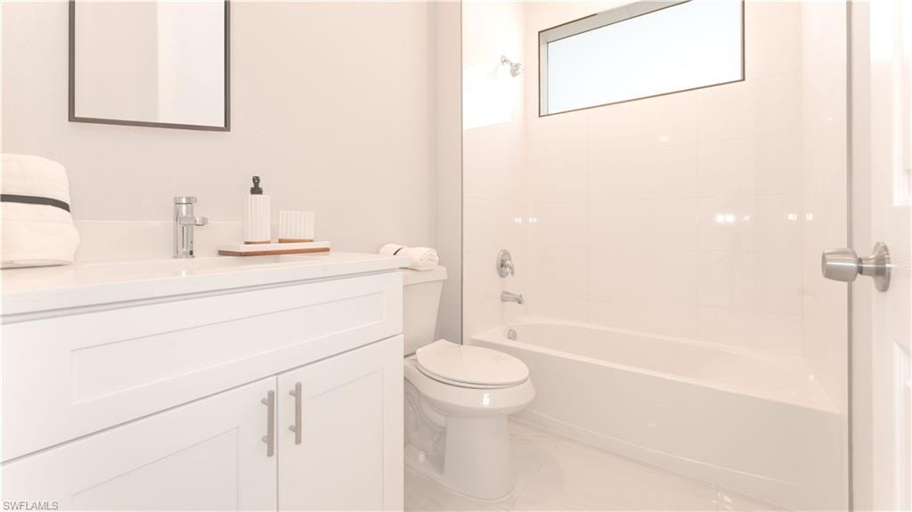Full bathroom featuring vanity, tiled shower / bath combo, and toilet