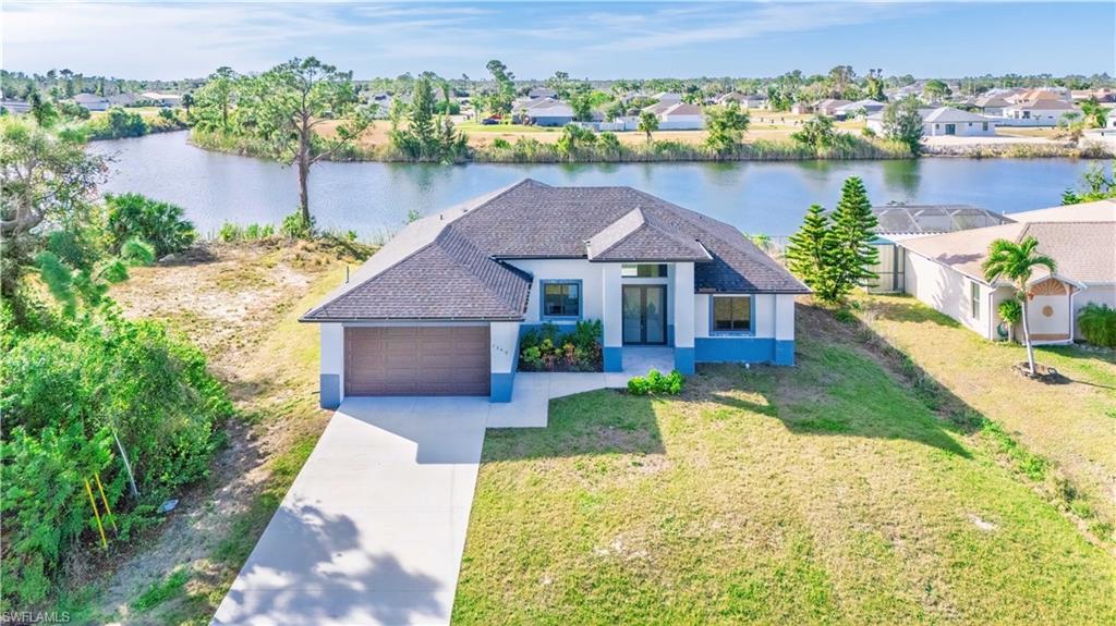 View of front facade with a front yard, a garage, and a water view