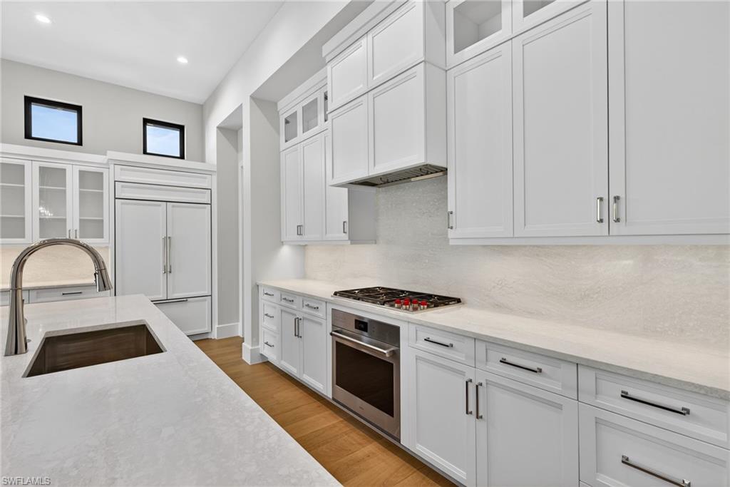 Kitchen with glass fronted cabinets, white cabinetry, stainless steel appliances, and recessed lighting