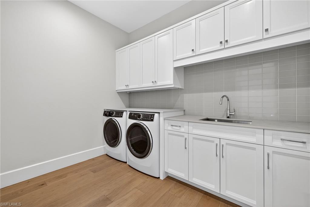 Laundry area with light wood flooring, independent washer and dryer, and lots of cabinet space