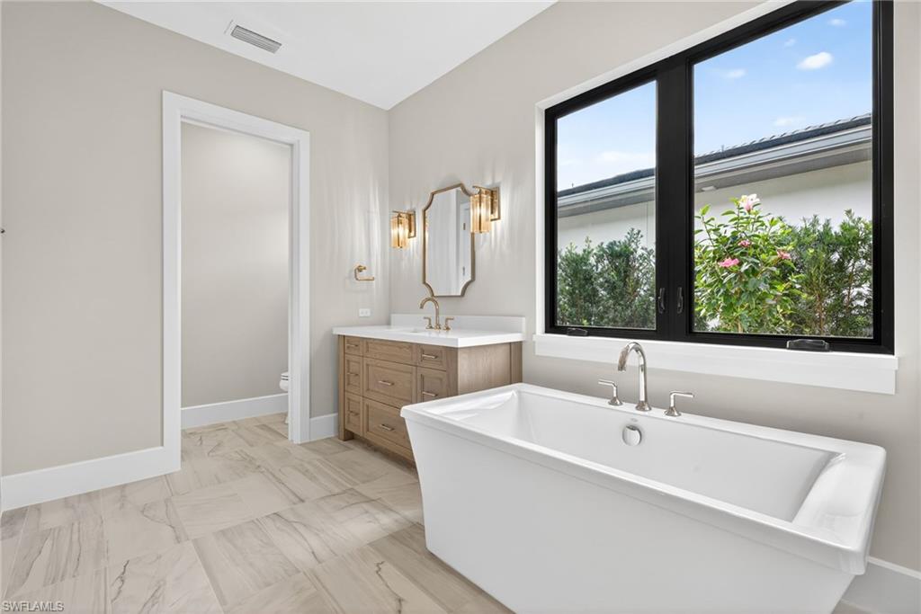 Bathroom with a soaking tub, vanity, and light marble finish floors