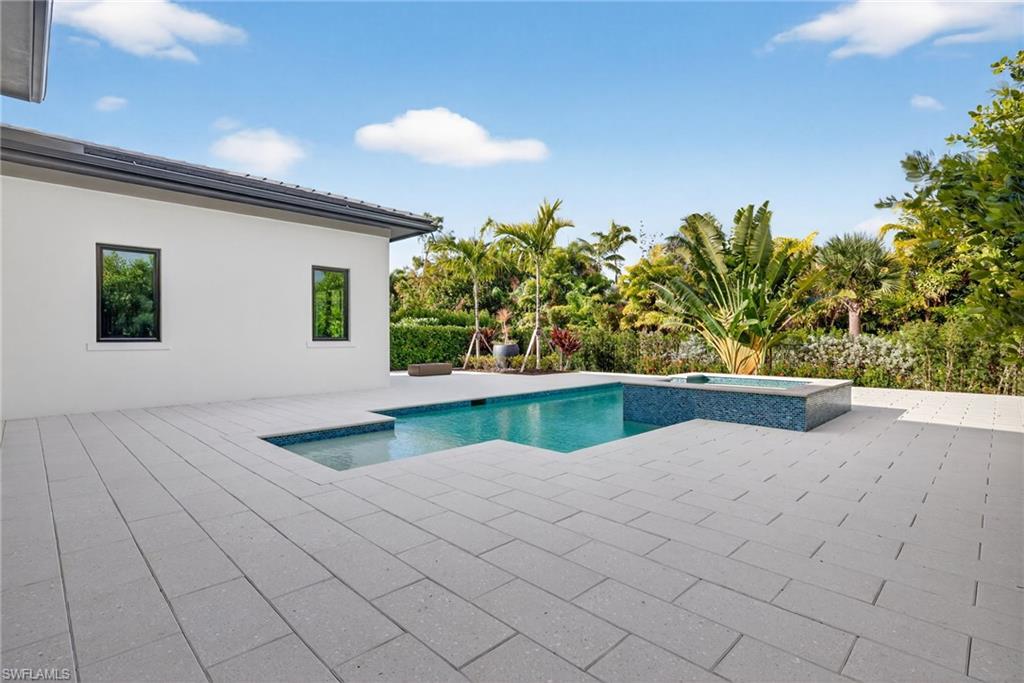 pool /spa with a patio area featuring fire pit surrounded by tropical trees and plantings