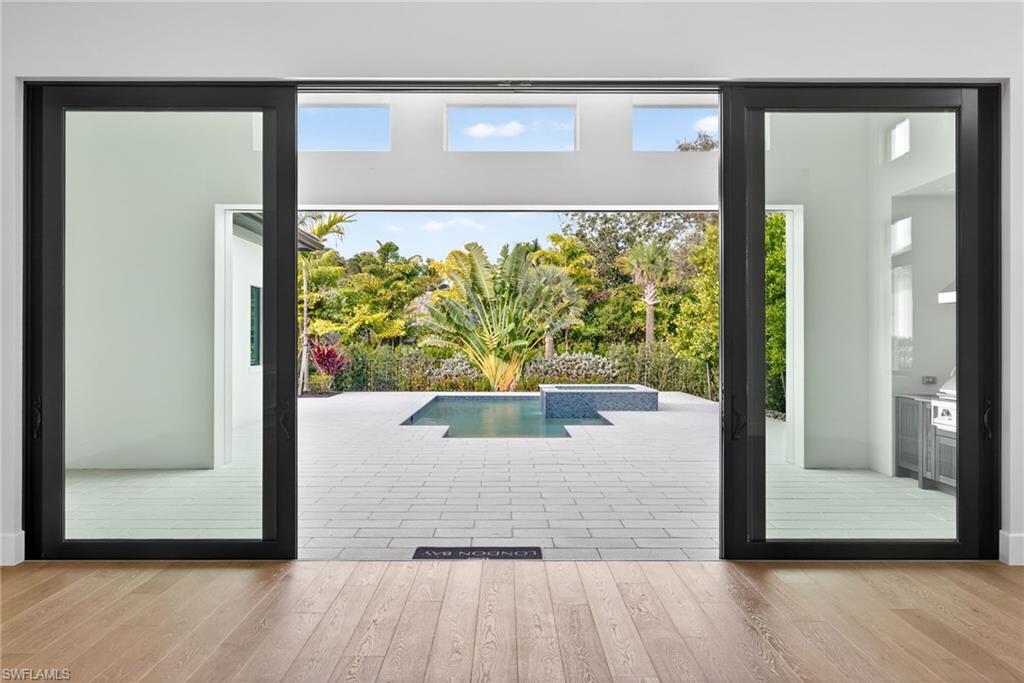 The open great room plan includes 10' tall sliding glass doors that lead to a covered area equipped with an outdoor kitchen, and fire table overlooking the picturesque open air resort style custom pool and spa.