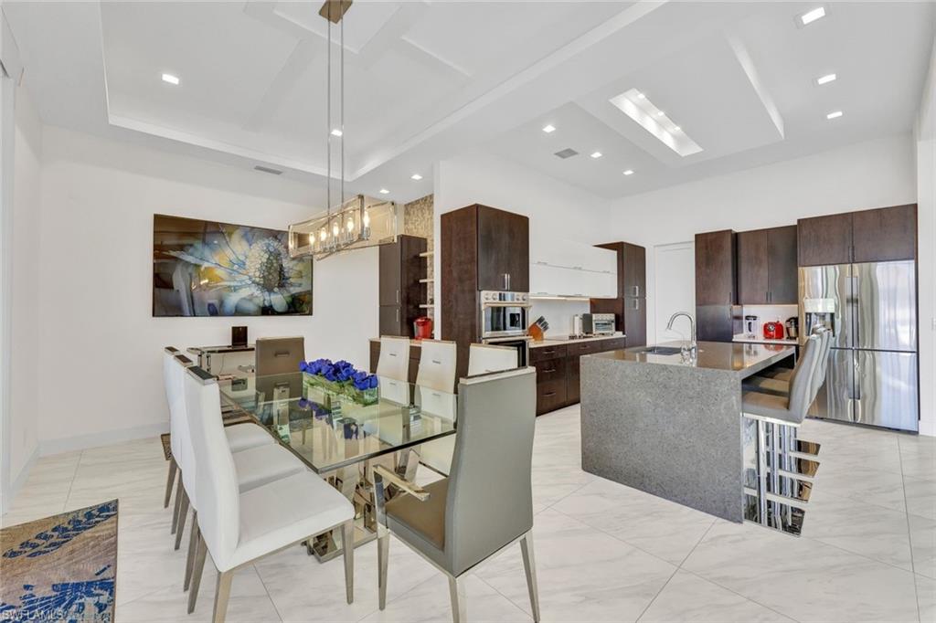 Dining area has a coffee bar with additional sink & concealed coffee maker cabinet complete with tiled accent wall & floating shelves