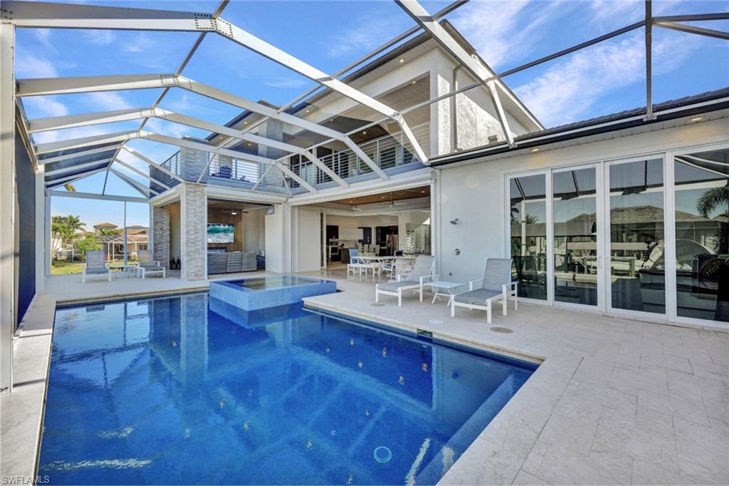 Massive screened patio area with a heated pool/spa, outdoor kitchen & a half bath