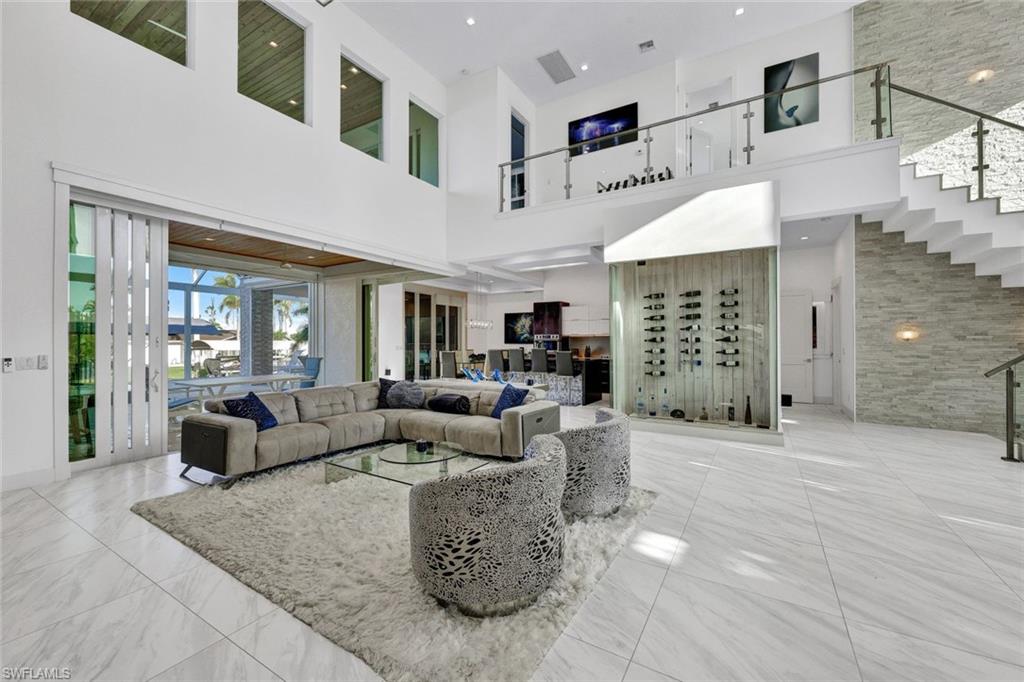 Massive living area with floating bottle design wine room that has mitered glass doors and access lighting