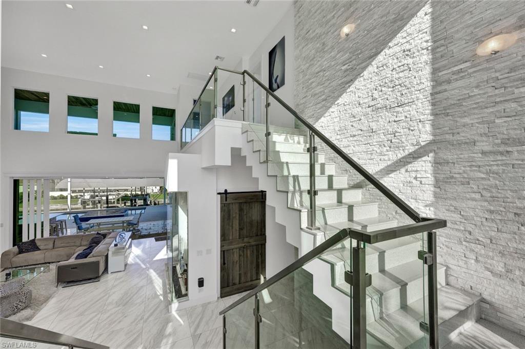 Floating Staircase with solid quartz treads & glass railings seated against a 25' white quartz stack stone accent wall and rock bed