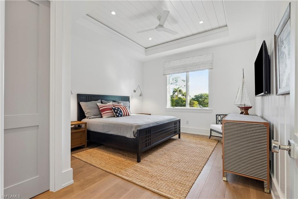 Bedroom featuring wood ceiling, ceiling fan, wood-type flooring, and a raised ceiling