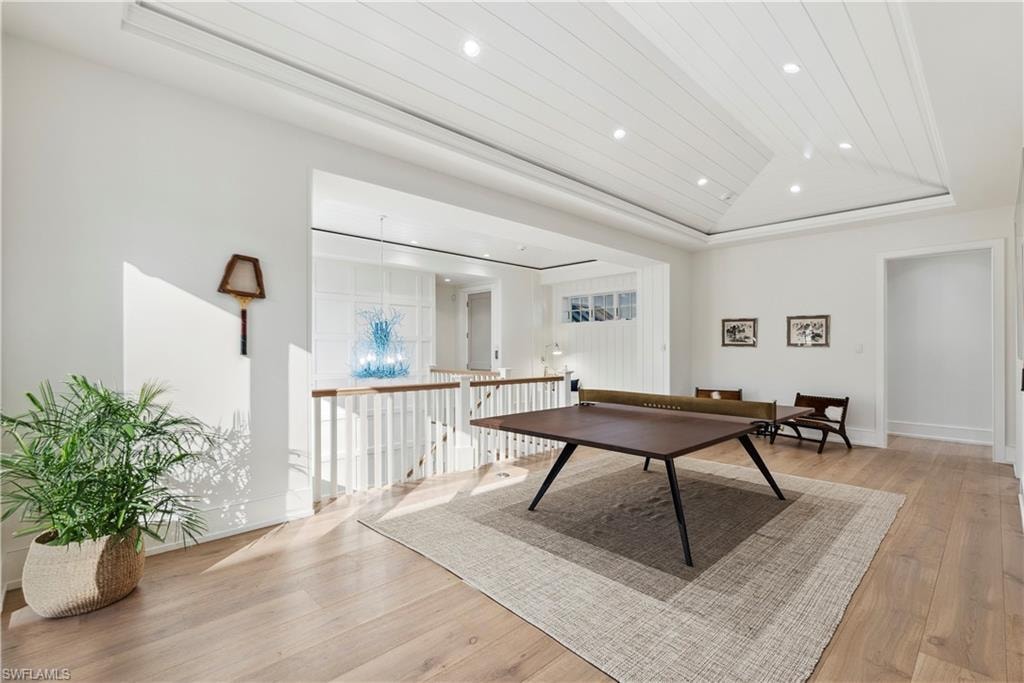 Rec room with lofted ceiling, light hardwood / wood-style floors, a raised ceiling, and wooden ceiling