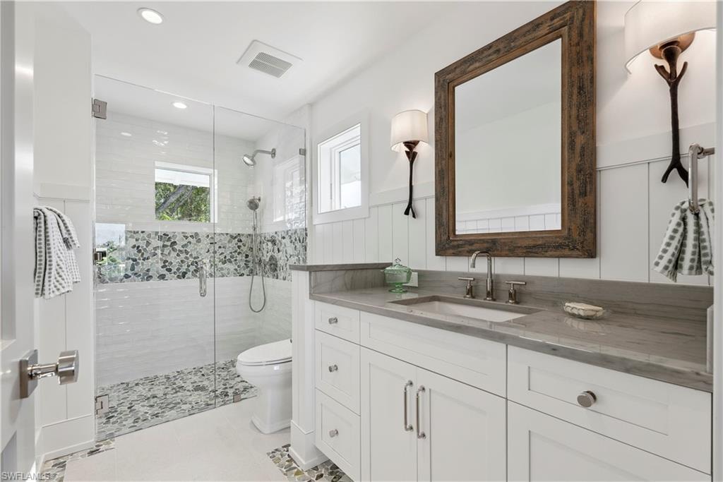 Bathroom with vanity, toilet, an enclosed shower, and tile patterned flooring