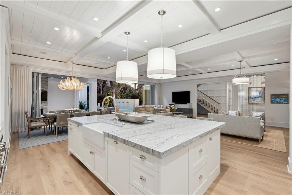 Kitchen with white cabinetry, sink, a large island, and pendant lighting