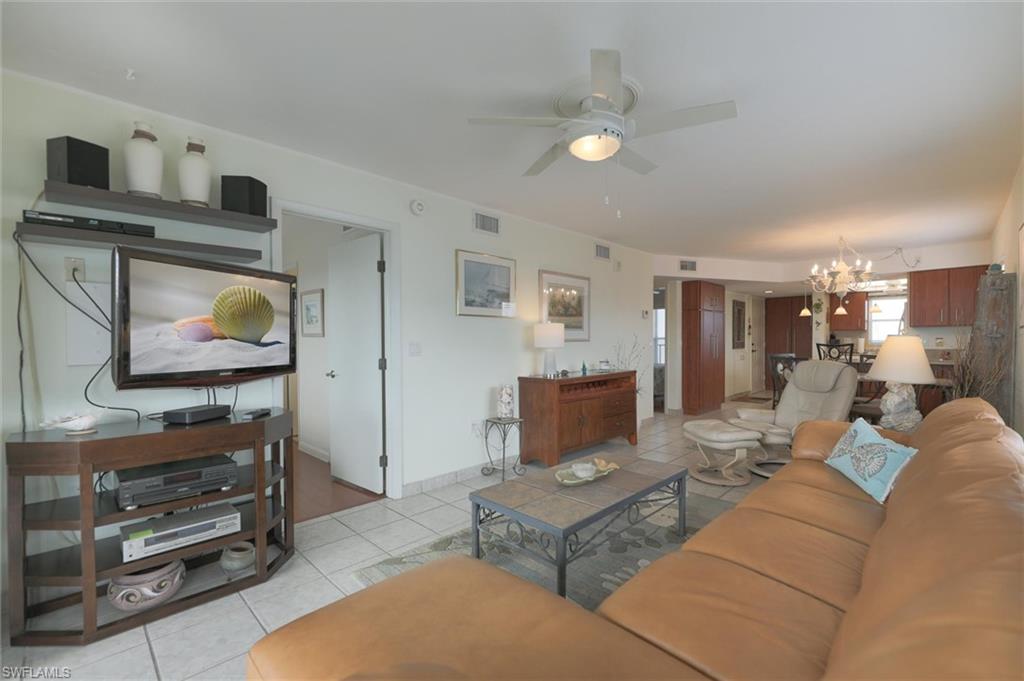 Tiled living room featuring ceiling fan with notable chandelier