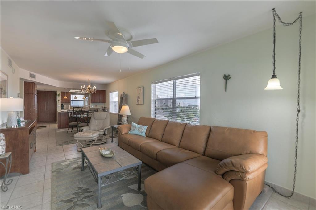 Living room featuring light tile floors and ceiling fan with notable chandelier