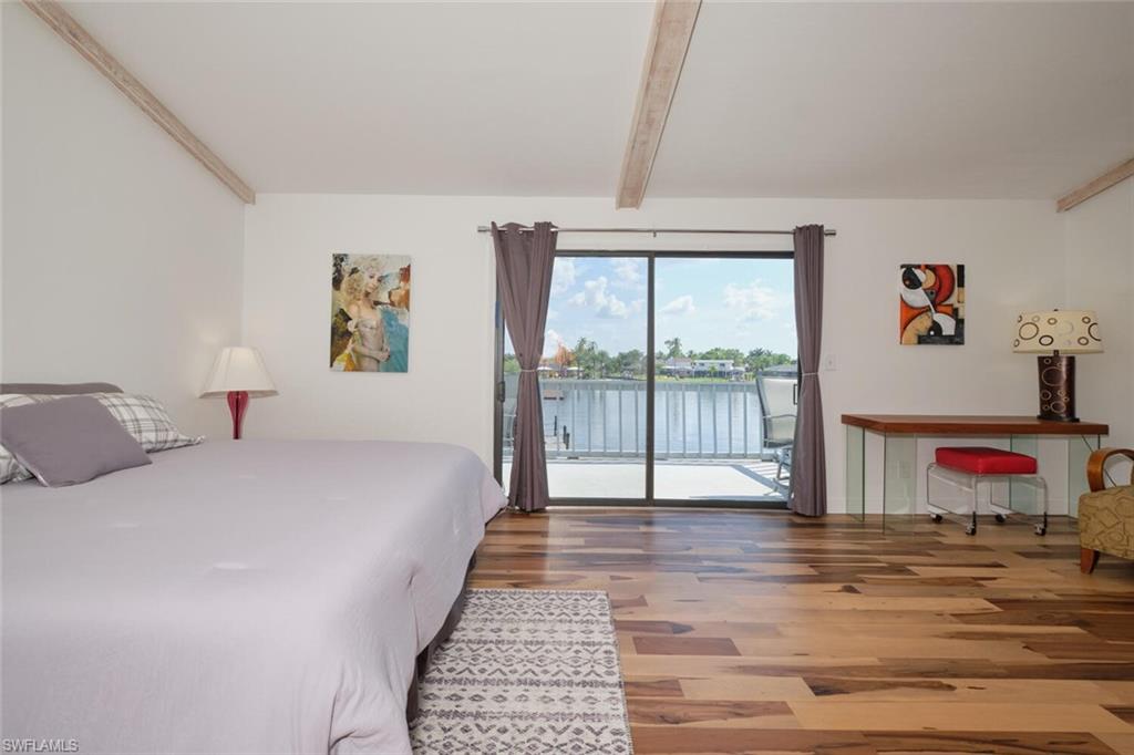 Bedroom with dark hardwood / wood-style floors, beam ceiling, and access to exterior