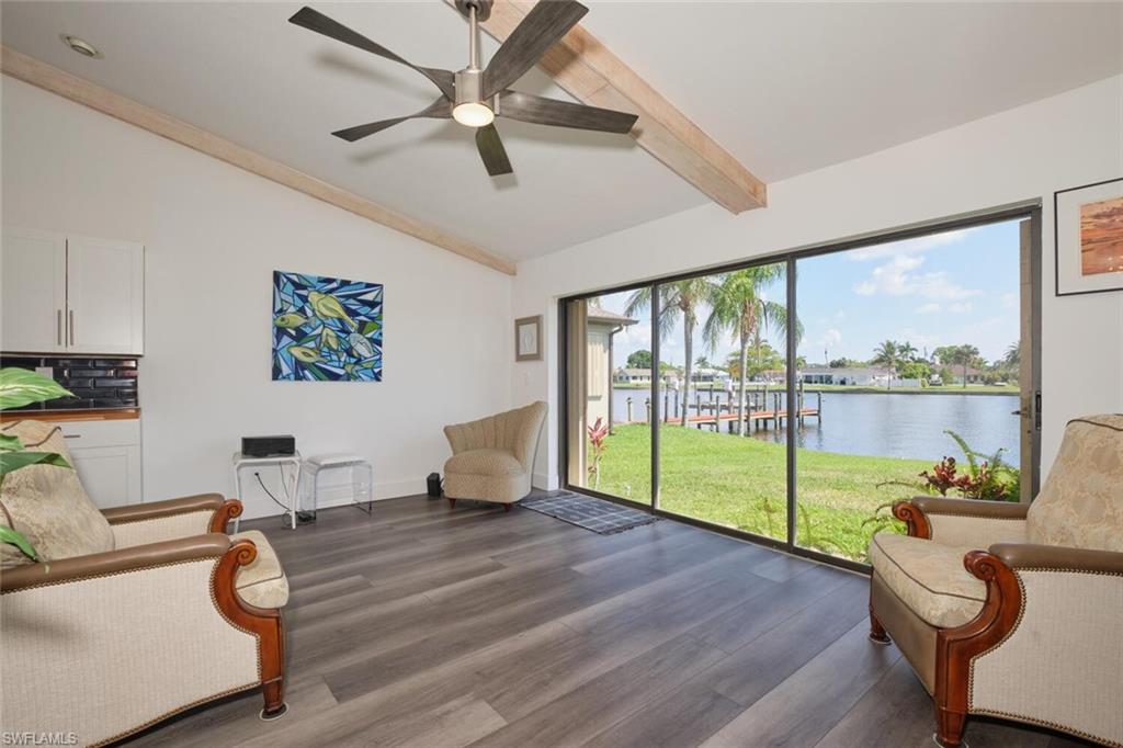 Living area featuring vaulted ceiling with beams, a water view, dark hardwood / wood-style flooring, and ceiling fan
