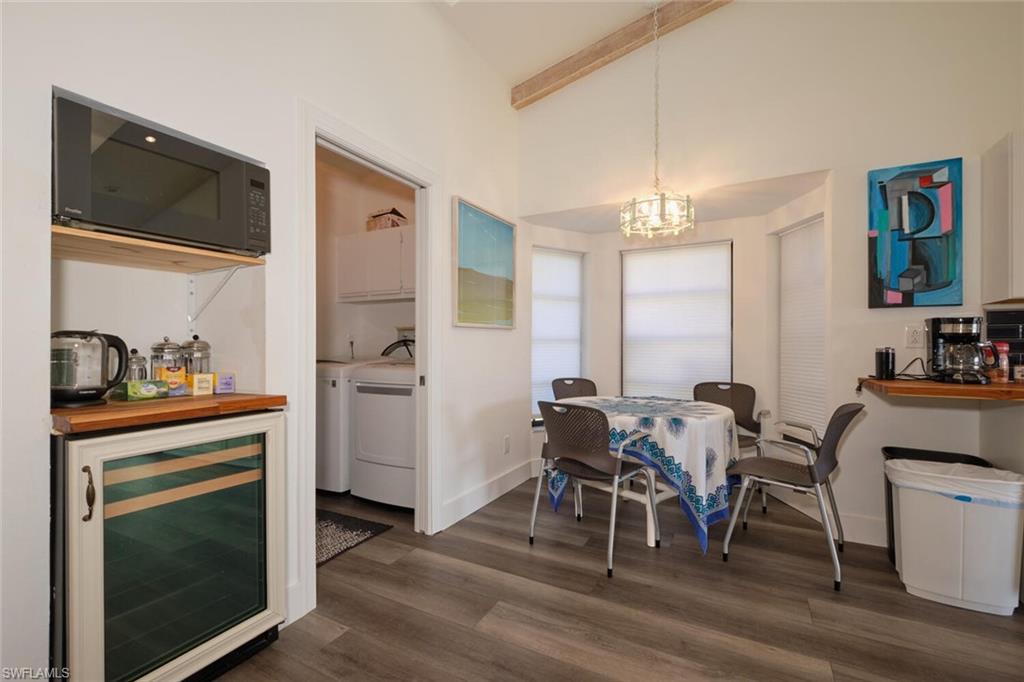 Dining space with beverage cooler, independent washer and dryer, vaulted ceiling, dark hardwood / wood-style flooring, and a chandelier