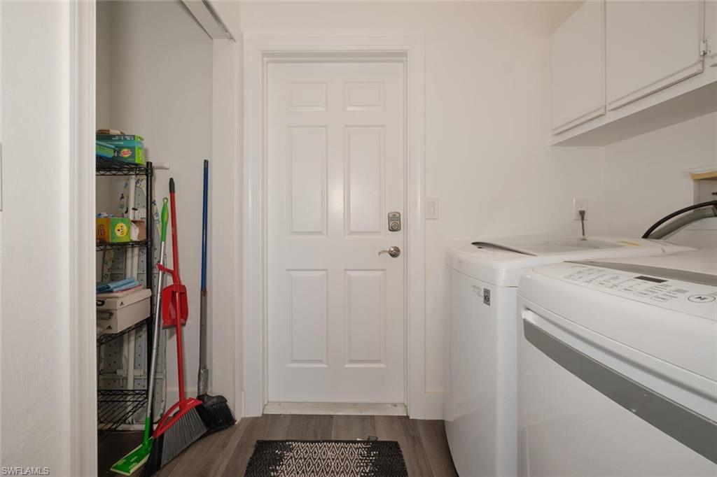 Laundry room with hardwood / wood-style floors, washing machine and dryer, and cabinets