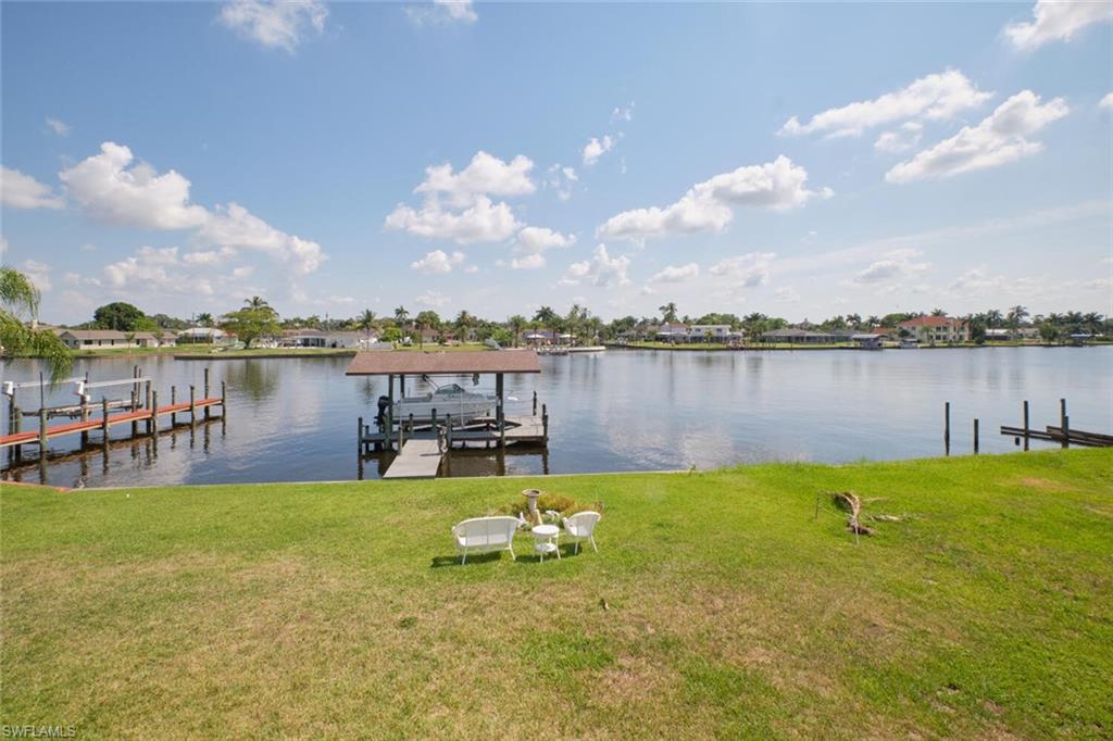 View of dock featuring a lawn and a water view