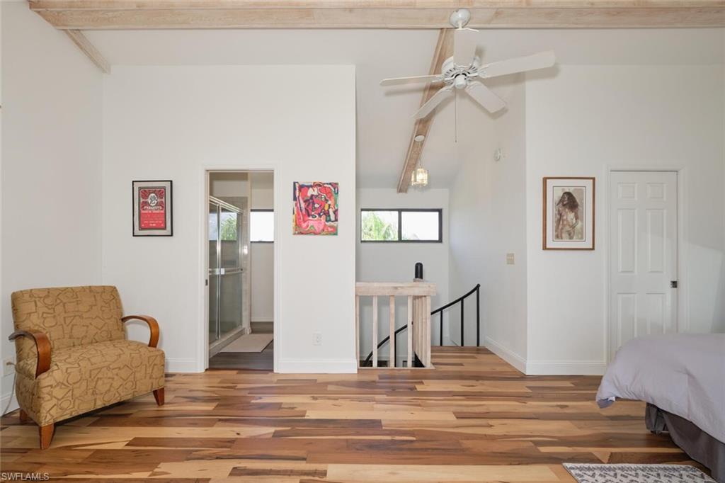 Bedroom featuring wood-type flooring, ceiling fan, ensuite bath, and beam ceiling